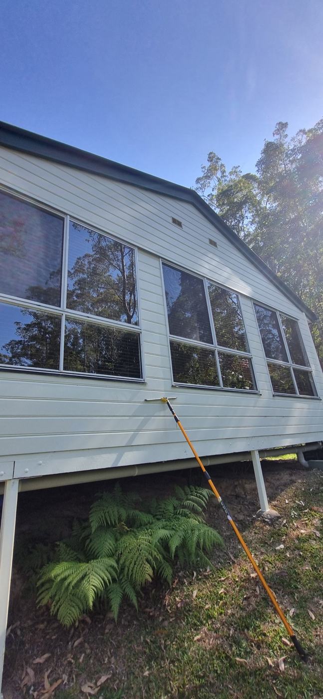 Window cleaning pole against a weatherboard house after cleaning the windows
